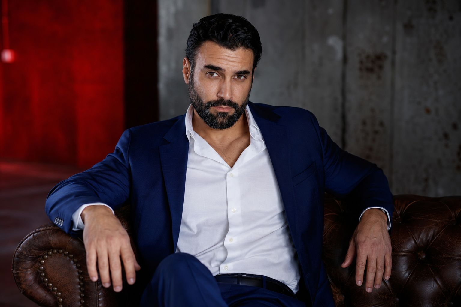 A.J. Castro seated in a navy suit on a leather sofa